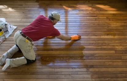 Foto van een man die een houten vloer onderhoudt door deze te behandelen met houten vloerolie